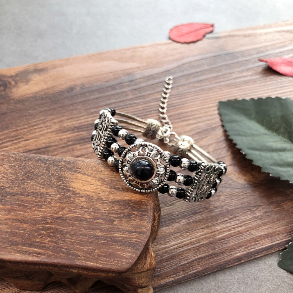 Vintage bohemian ethnic black beaded bracelet with silver engraved accents, displayed on a wooden surface, ideal for boho fashion enthusiasts