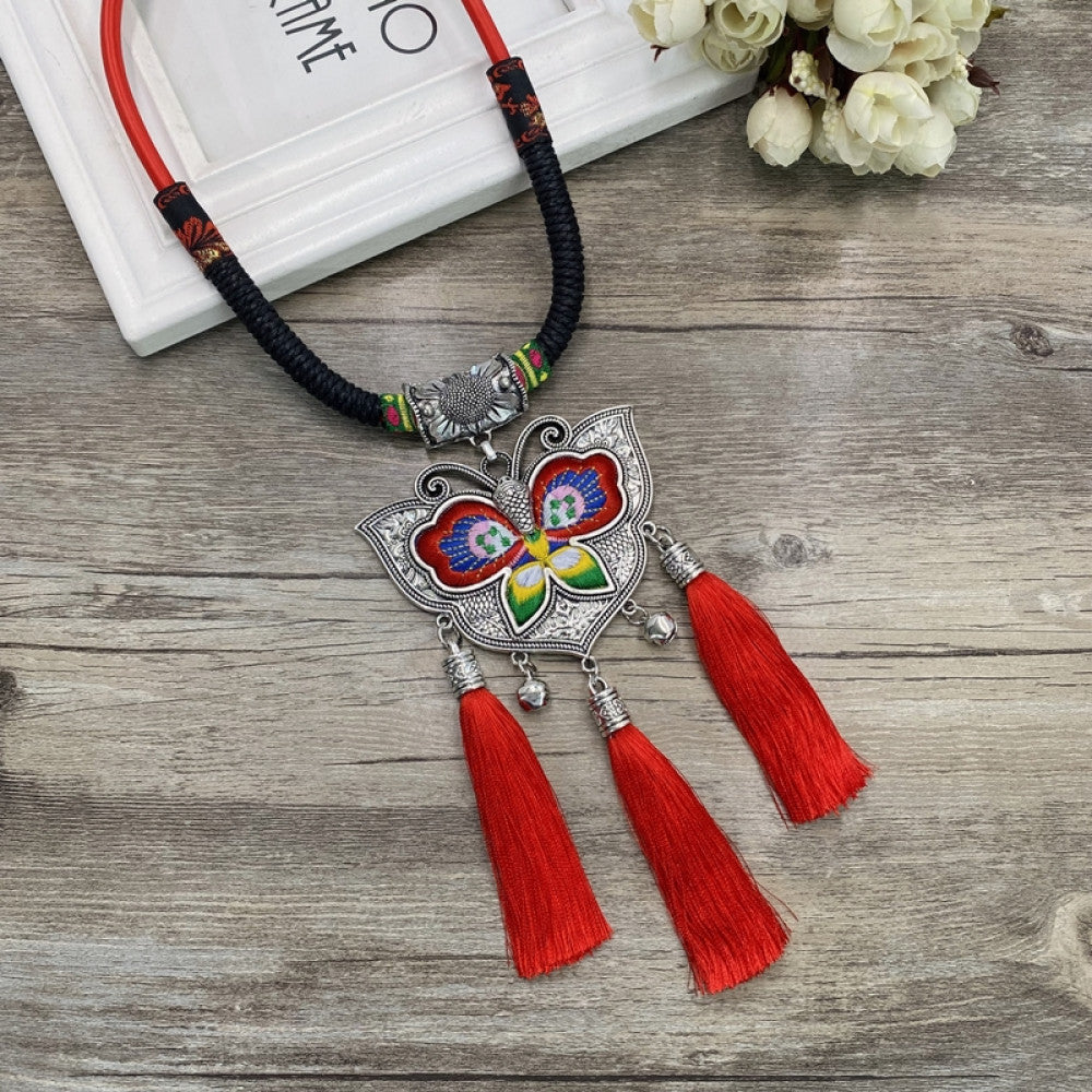 Vintage bohemian ethnic necklace with colorful enamel floral pendant and silver bell tassels, displayed on a wooden surface with decorative accents, ideal for boho fashion enthusiasts 04