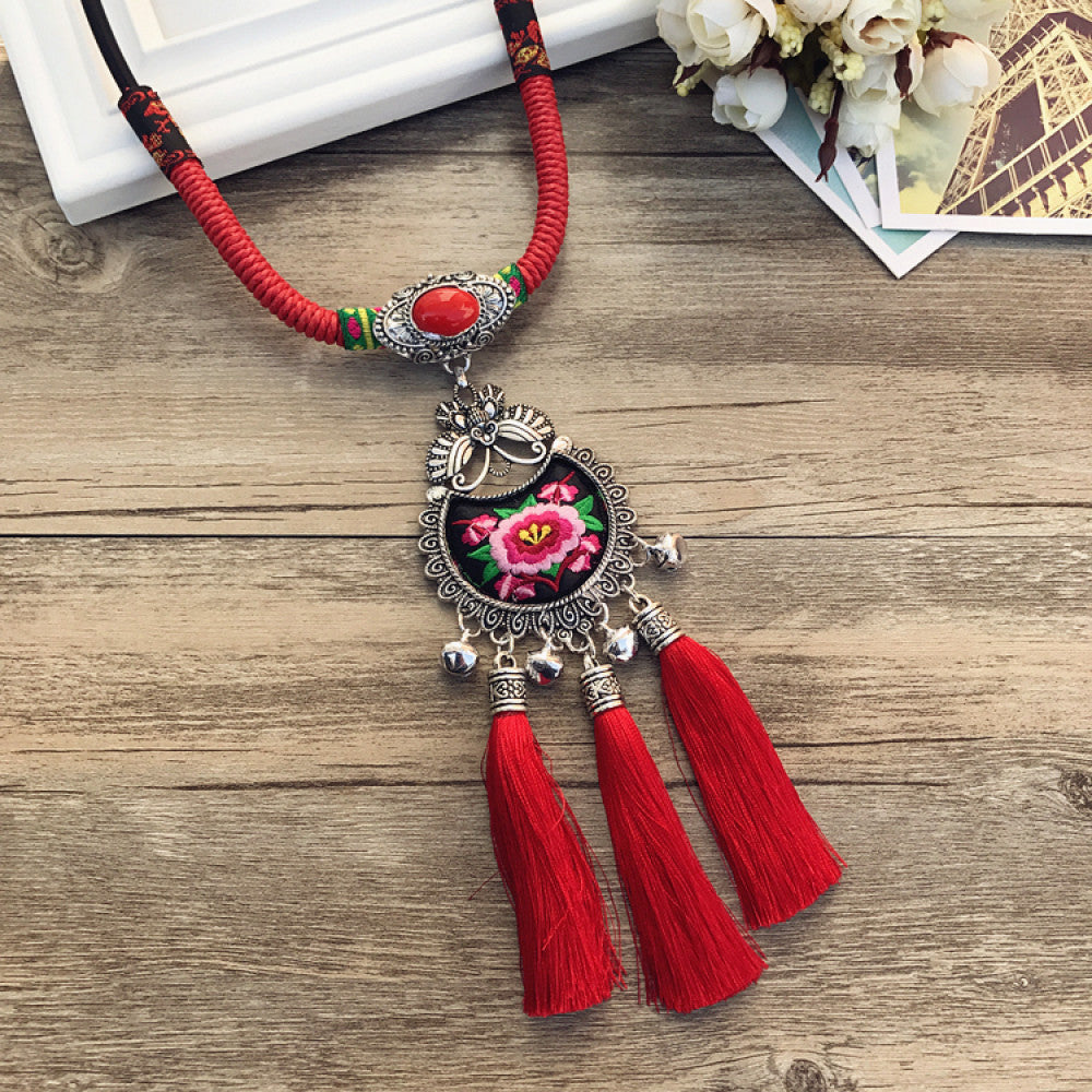 Vintage bohemian ethnic necklace with colorful enamel floral pendant and silver bell tassels, displayed on a wooden surface with decorative accents, ideal for boho fashion enthusiasts 07