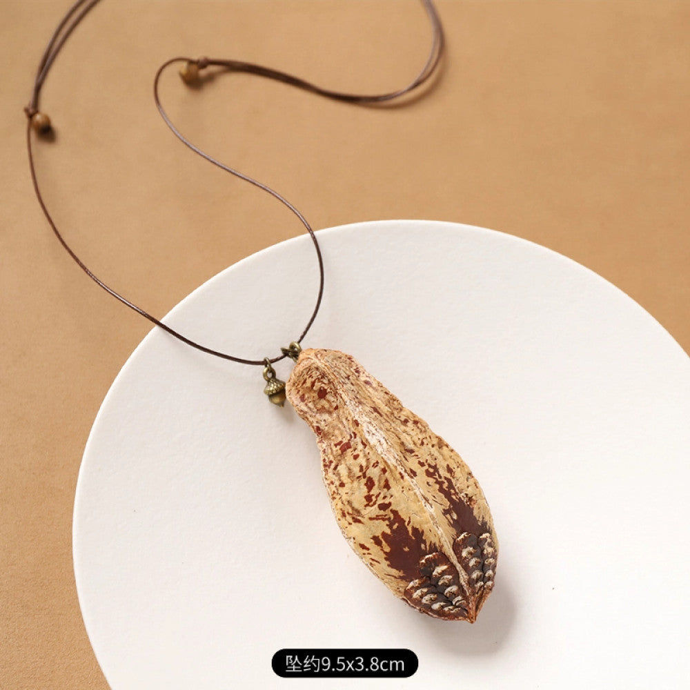 Vintage bohemian ethnic necklace with natural seed pendant, featuring earthy brown tones and cord design, displayed on a white plate against a neutral background, ideal for boho fashion enthusiasts 04