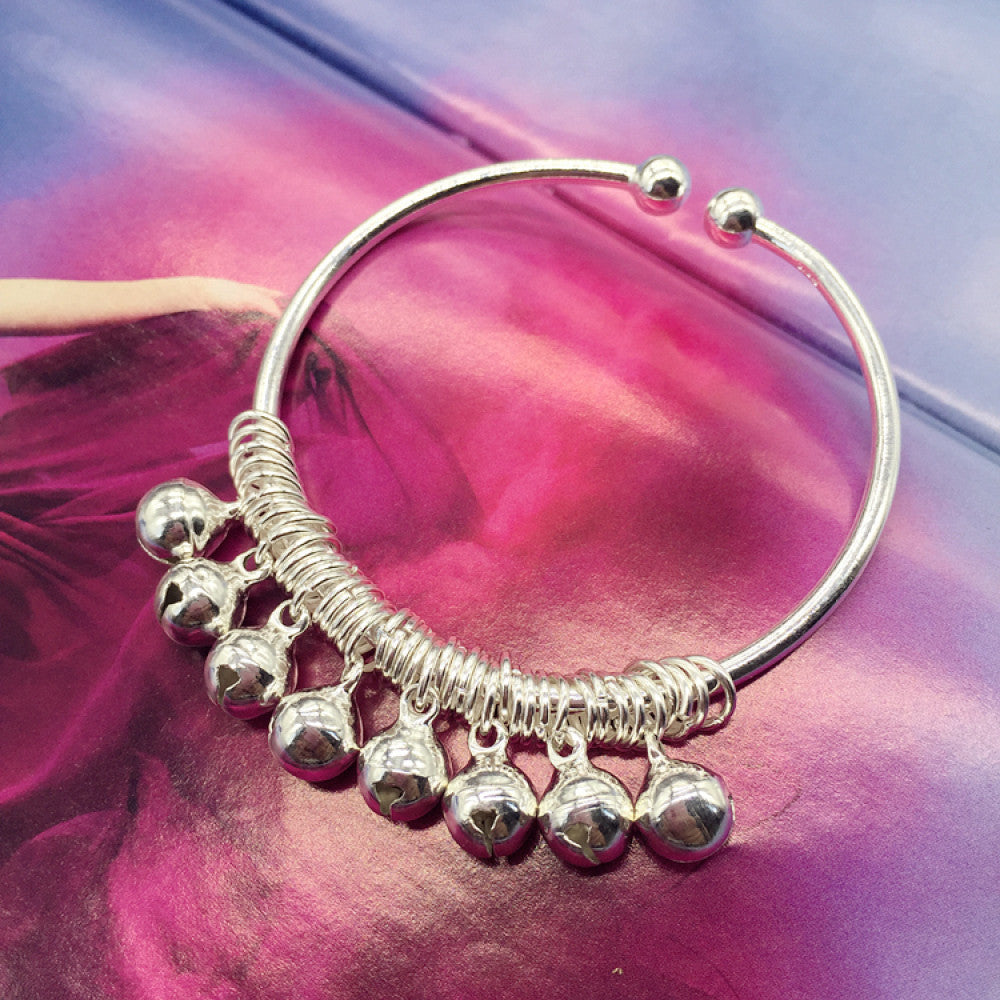 Vintage bohemian ethnic silver-tone bangle adorned with heart-shaped bell charms, displayed on a pink floral background, ideal for boho fashion enthusiasts 01