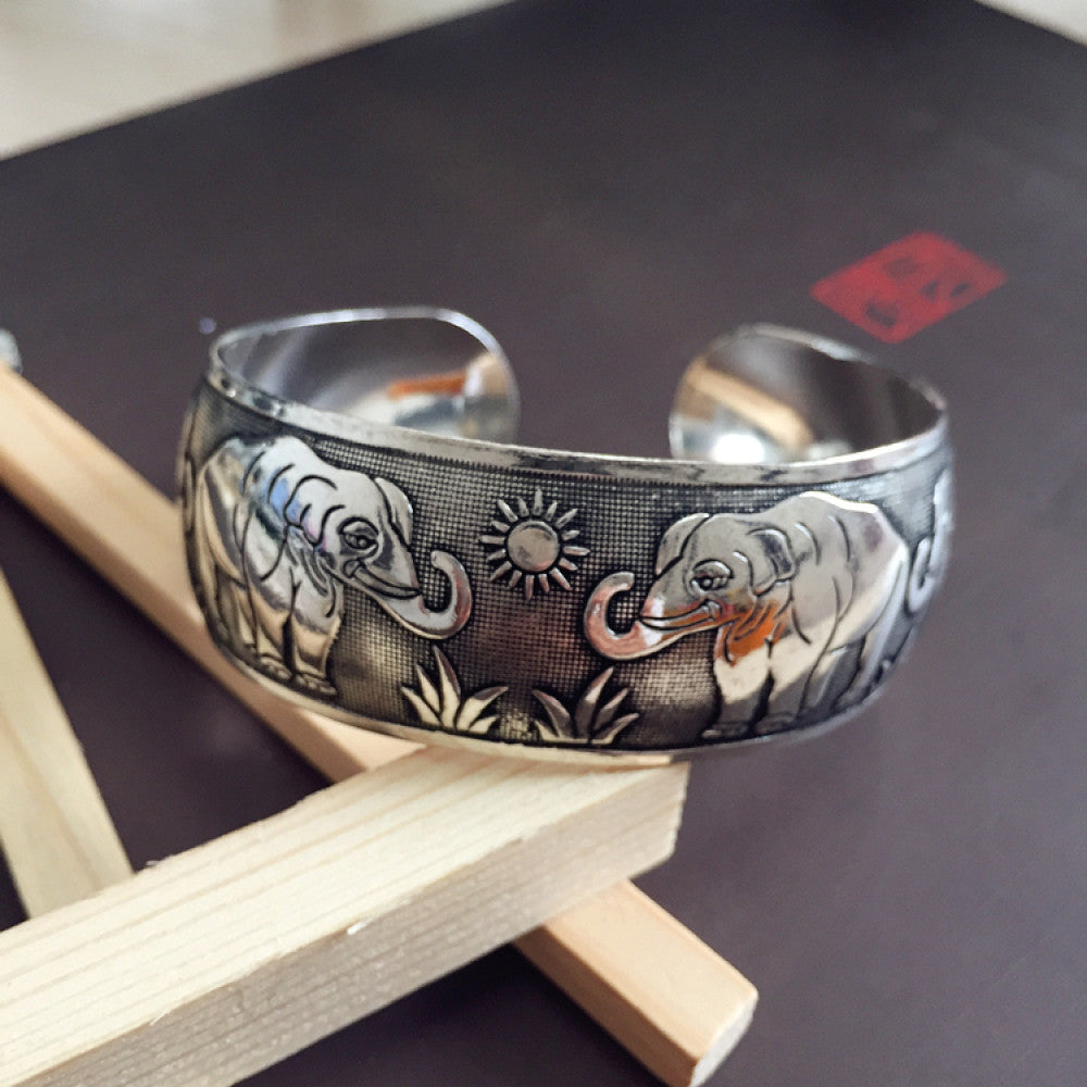 Vintage bohemian ethnic silver-tone cuff bracelet with intricate traditional motif engravings, displayed on wooden accents, ideal for boho and ethnic fashion enthusiasts 01