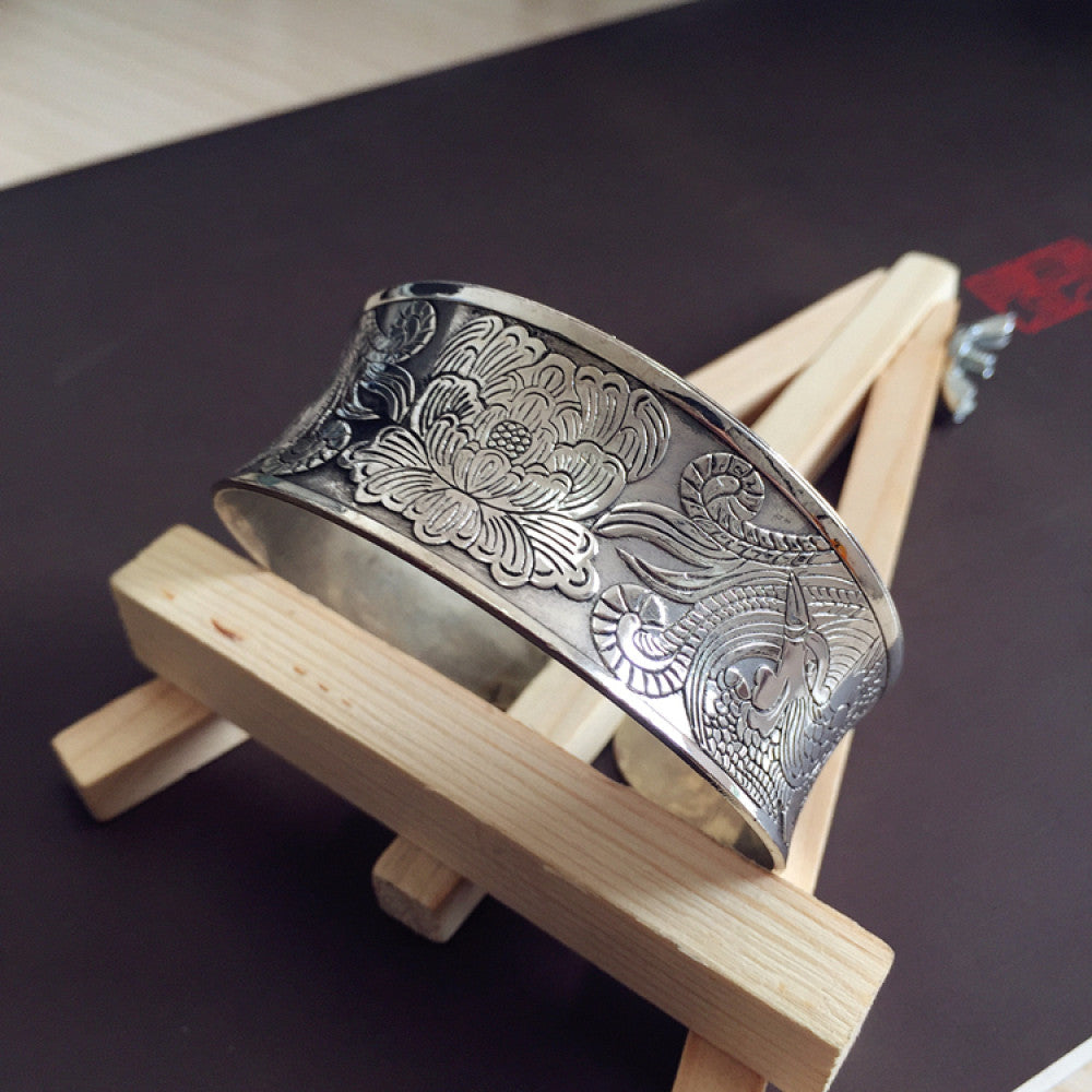 Vintage bohemian ethnic silver-tone cuff bracelet with intricate traditional motif engravings, displayed on wooden accents, ideal for boho and ethnic fashion enthusiasts 03