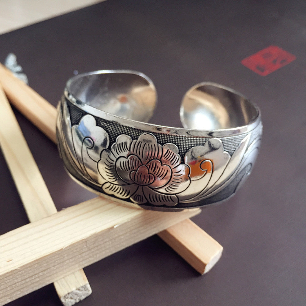 Vintage bohemian ethnic silver-tone cuff bracelet with intricate traditional motif engravings, displayed on wooden accents, ideal for boho and ethnic fashion enthusiasts 04