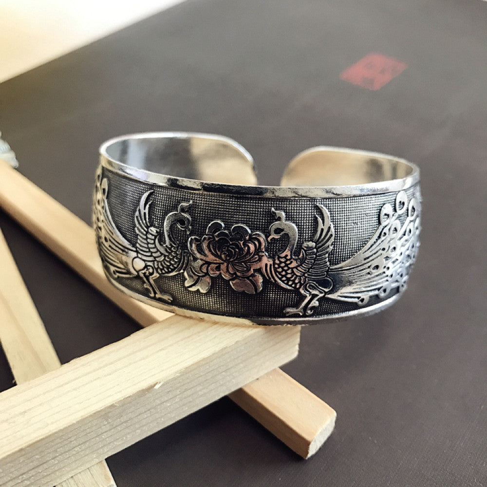 Vintage bohemian ethnic silver-tone cuff bracelet with intricate traditional motif engravings, displayed on wooden accents, ideal for boho and ethnic fashion enthusiasts 05