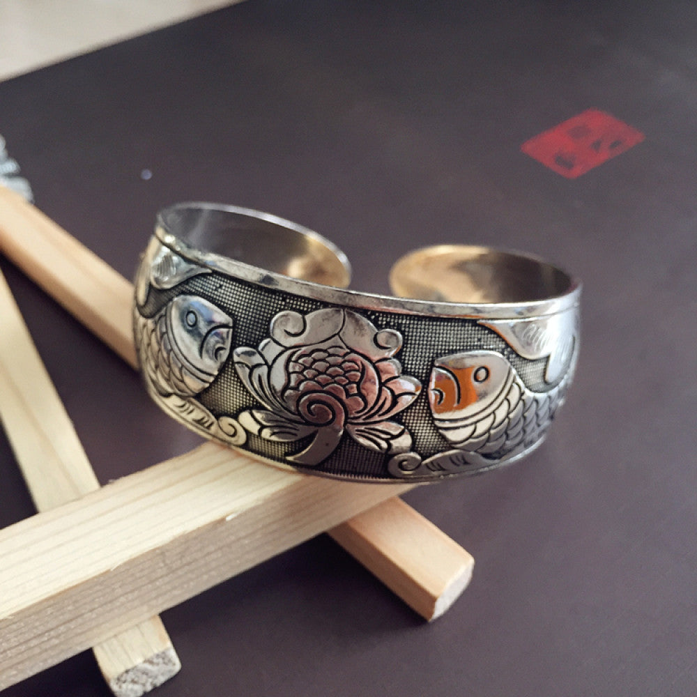 Vintage bohemian ethnic silver-tone cuff bracelet with intricate traditional motif engravings, displayed on wooden accents, ideal for boho and ethnic fashion enthusiasts 06