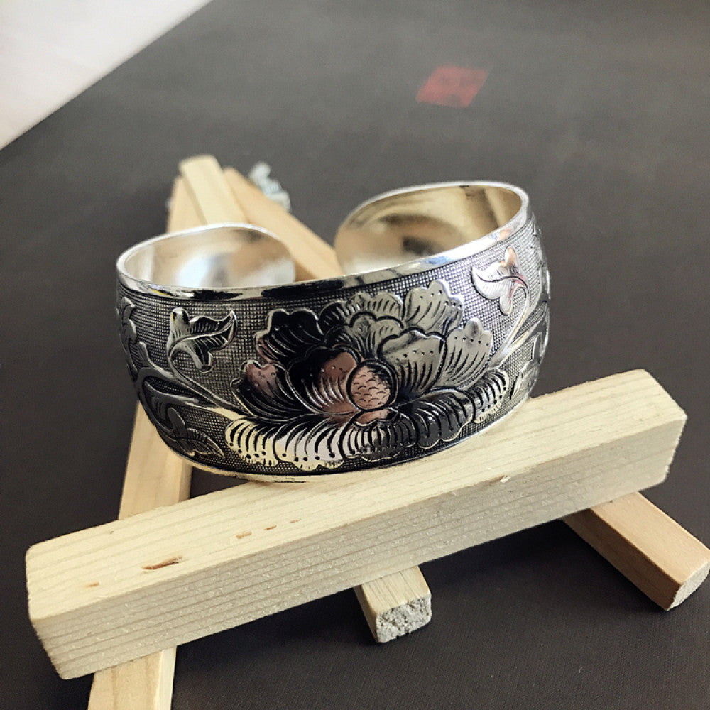 Vintage bohemian ethnic silver-tone cuff bracelet with intricate traditional motif engravings, displayed on wooden accents, ideal for boho and ethnic fashion enthusiasts 09