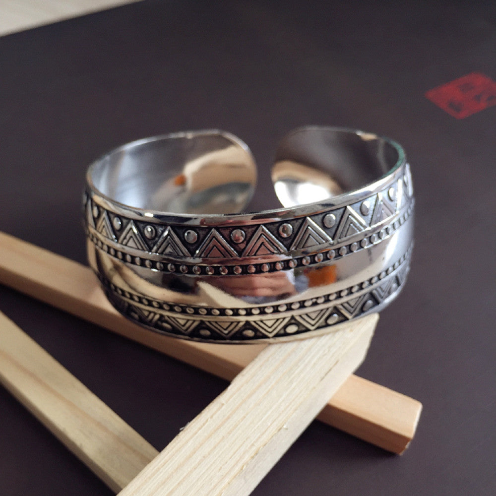 Vintage bohemian ethnic silver-tone cuff bracelet with intricate traditional motif engravings, displayed on wooden accents, ideal for boho and ethnic fashion enthusiasts 10