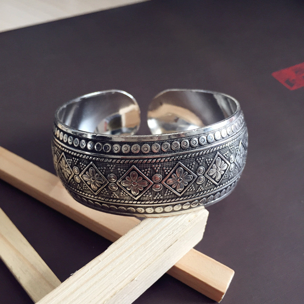 Vintage bohemian ethnic silver-tone cuff bracelet with intricate traditional motif engravings, displayed on wooden accents, ideal for boho and ethnic fashion enthusiasts 15