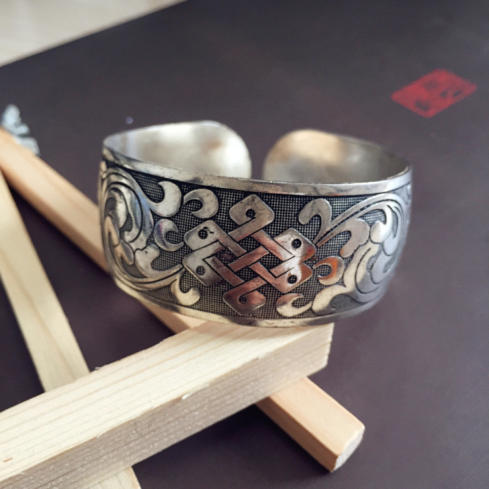 Vintage bohemian ethnic silver-tone engraved filigree cuff bracelet with intricate floral designs, displayed on wooden accents, ideal for boho and ethnic fashion enthusiasts 04