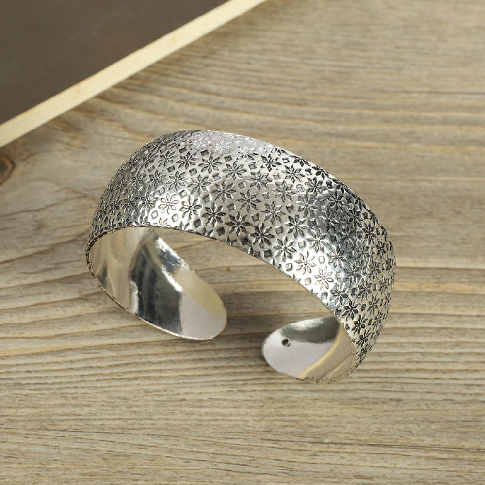 Vintage bohemian ethnic silver-tone engraved filigree cuff bracelet with intricate floral designs, displayed on wooden accents, ideal for boho and ethnic fashion enthusiasts 06