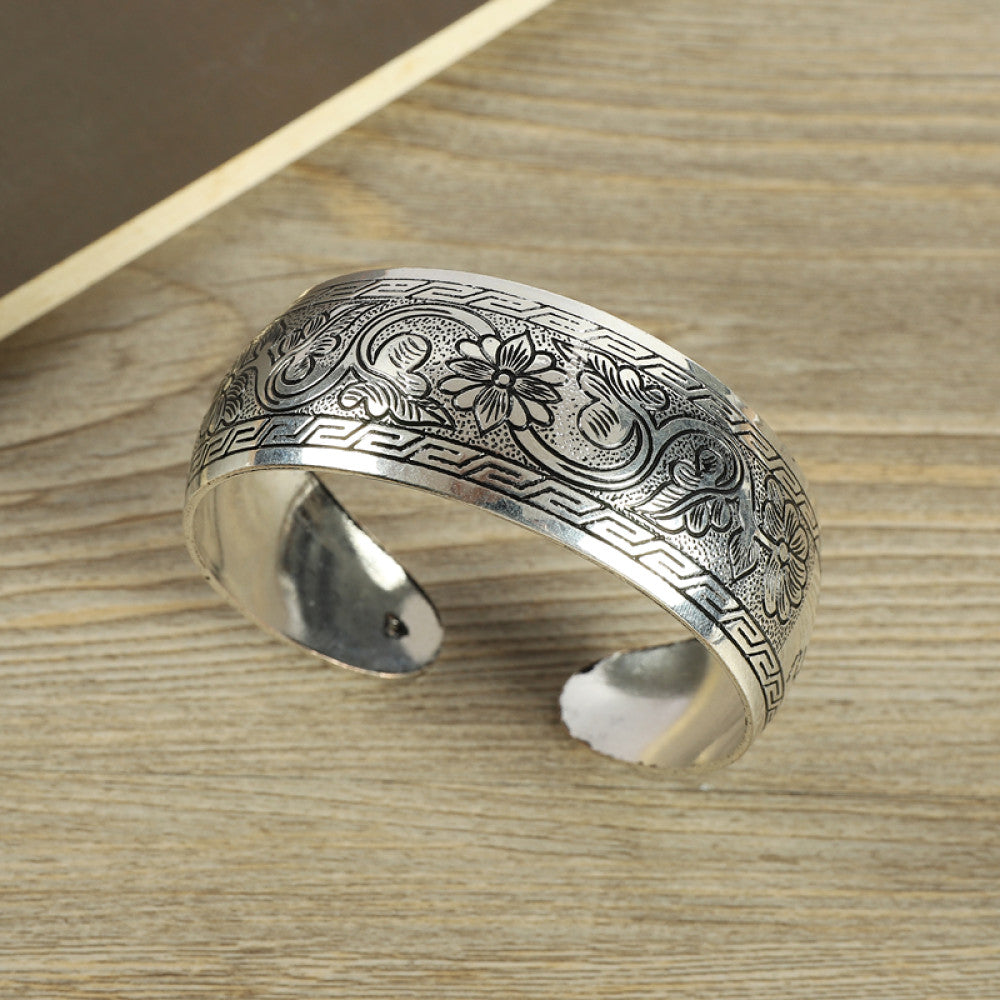 Vintage bohemian ethnic silver-tone engraved filigree cuff bracelet with intricate floral designs, displayed on wooden accents, ideal for boho and ethnic fashion enthusiasts 07