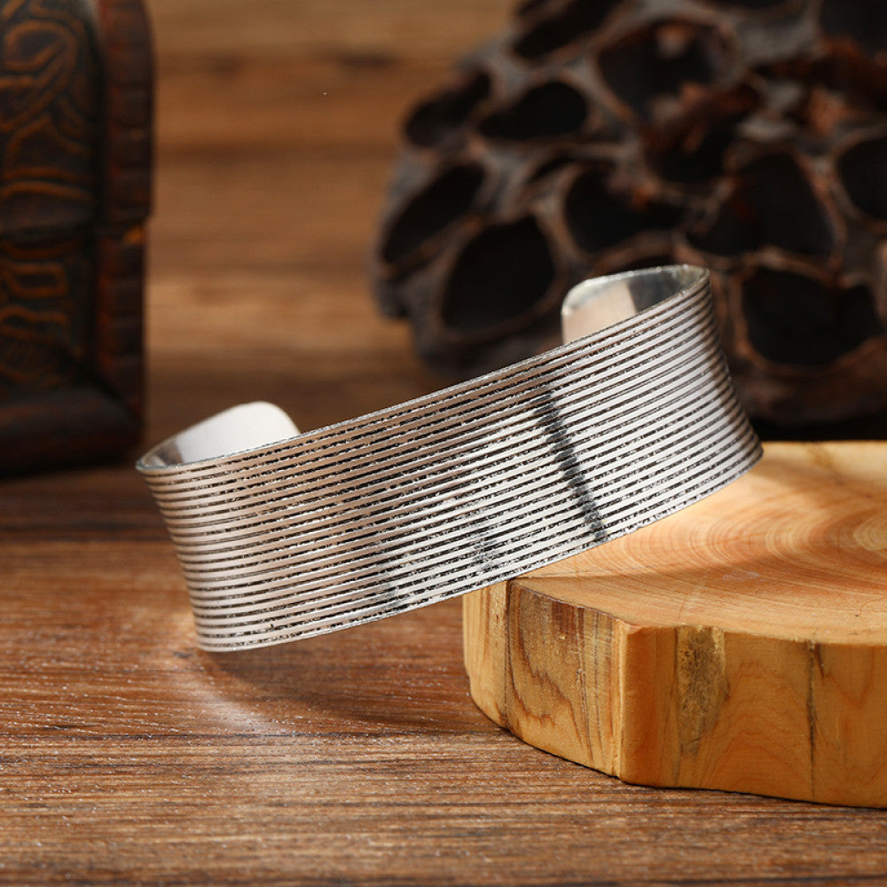 Vintage bohemian ethnic silver-tone cuff bracelet with intricate engraved floral designs, displayed on a wooden surface with rustic decor, ideal for boho and ethnic fashion enthusiasts 02