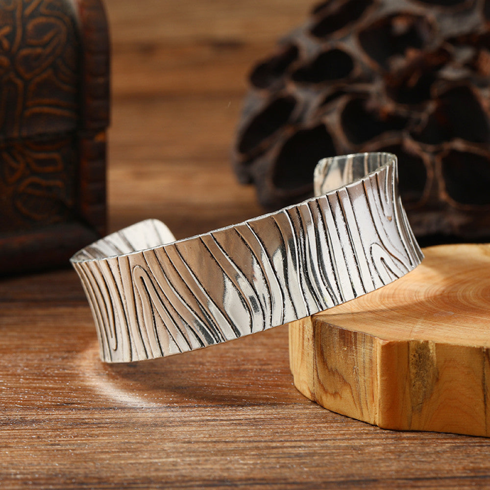 Vintage bohemian ethnic silver-tone cuff bracelet with intricate engraved floral designs, displayed on a wooden surface with rustic decor, ideal for boho and ethnic fashion enthusiasts 03