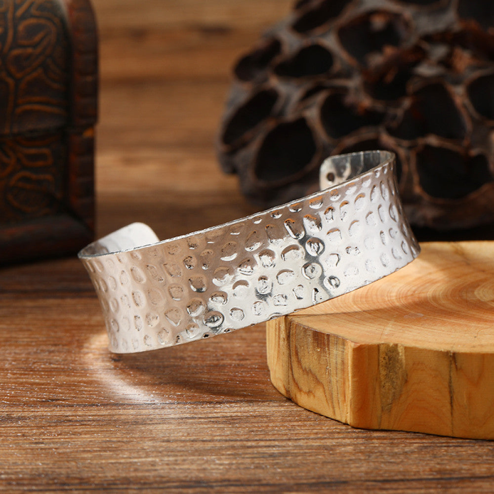 Vintage bohemian ethnic silver-tone cuff bracelet with intricate engraved floral designs, displayed on a wooden surface with rustic decor, ideal for boho and ethnic fashion enthusiasts 9