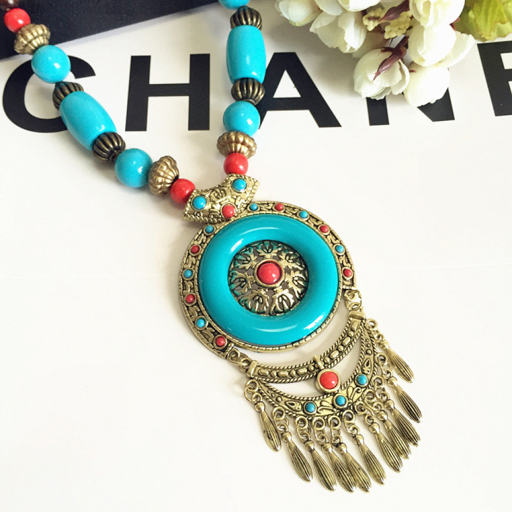 Vintage bohemian ethnic necklace with large red pendant, turquoise details, and tassel design, featuring antique bronze finish, ideal for boho fashion, displayed with floral and text accents against a white background 06