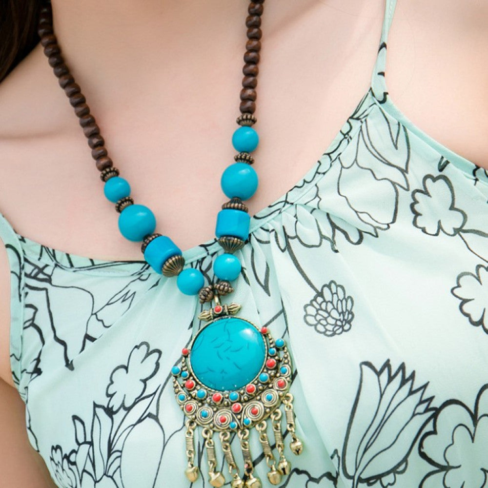 Vintage bohemian ethnic necklace with large red pendant, turquoise details, and tassel design, featuring antique bronze finish, ideal for boho fashion, displayed with floral and text accents against a white background 01