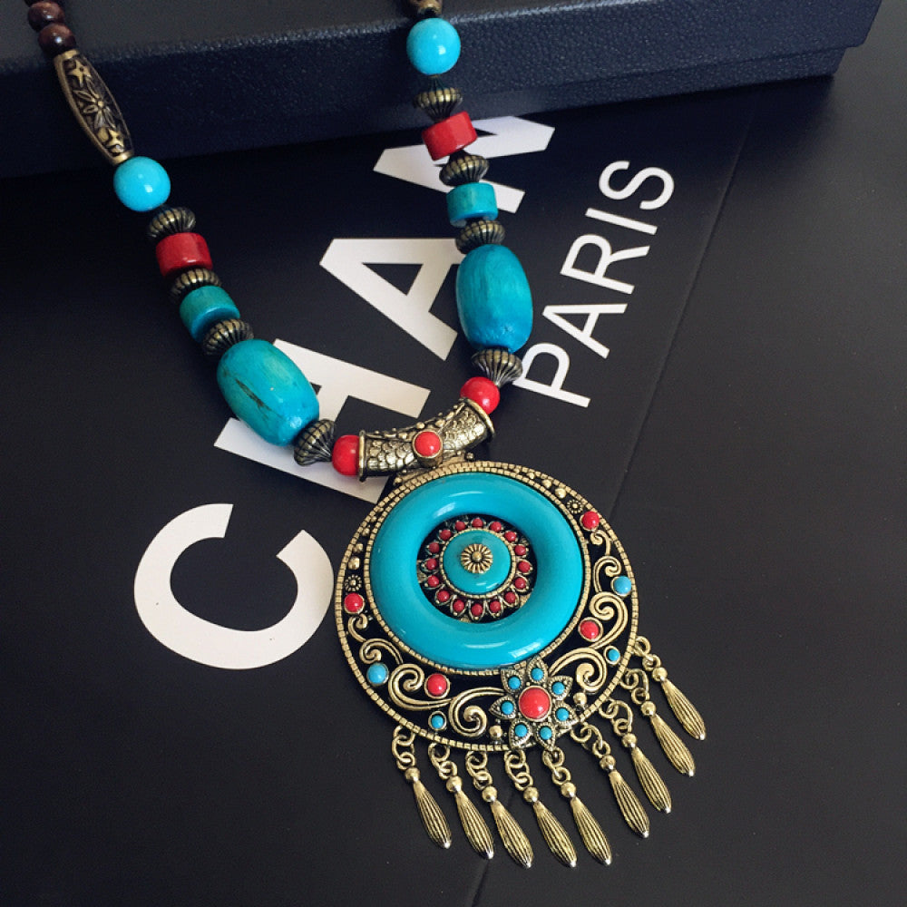 Vintage bohemian ethnic necklace with large red pendant, turquoise details, and tassel design, featuring antique bronze finish, ideal for boho fashion, displayed with floral and text accents against a white background 02