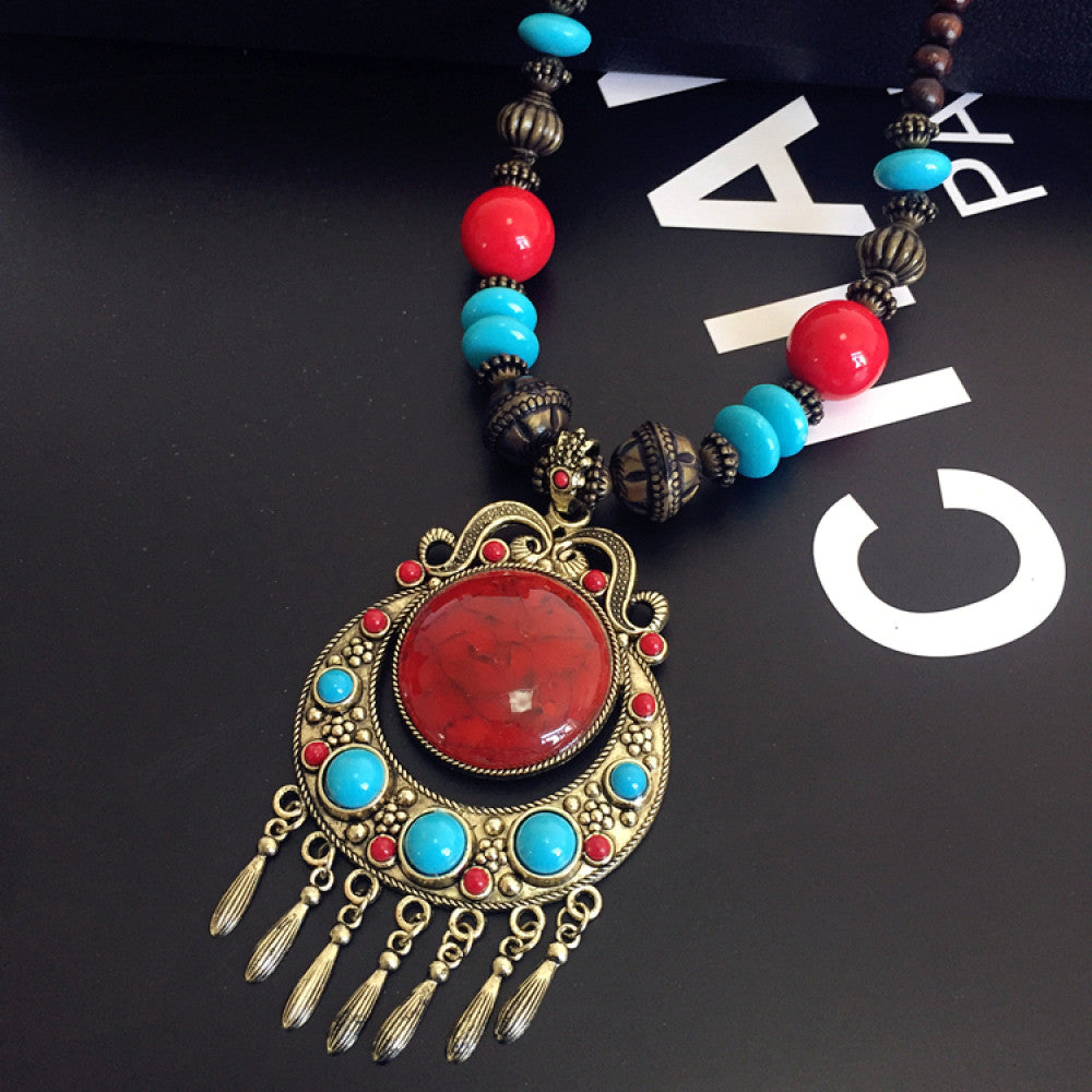 Vintage bohemian ethnic necklace with large red pendant, turquoise details, and tassel design, featuring antique bronze finish, ideal for boho fashion, displayed with floral and text accents against a white background 03
