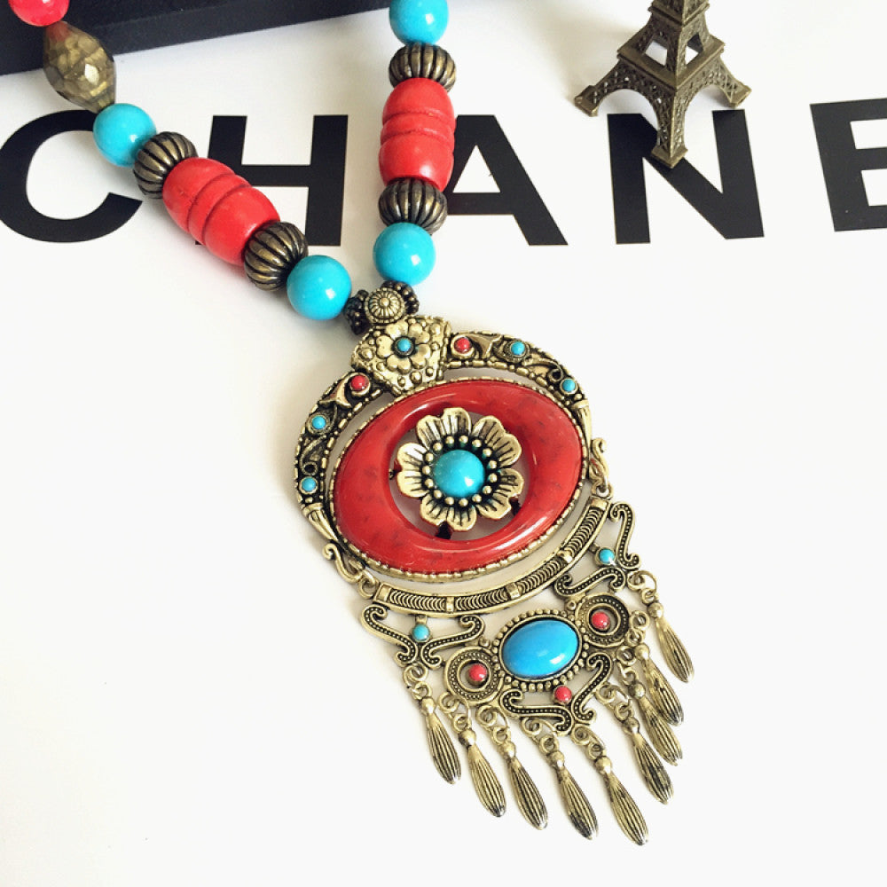 Vintage bohemian ethnic necklace with large red pendant, turquoise details, and tassel design, featuring antique bronze finish, ideal for boho fashion, displayed with floral and text accents against a white background 07