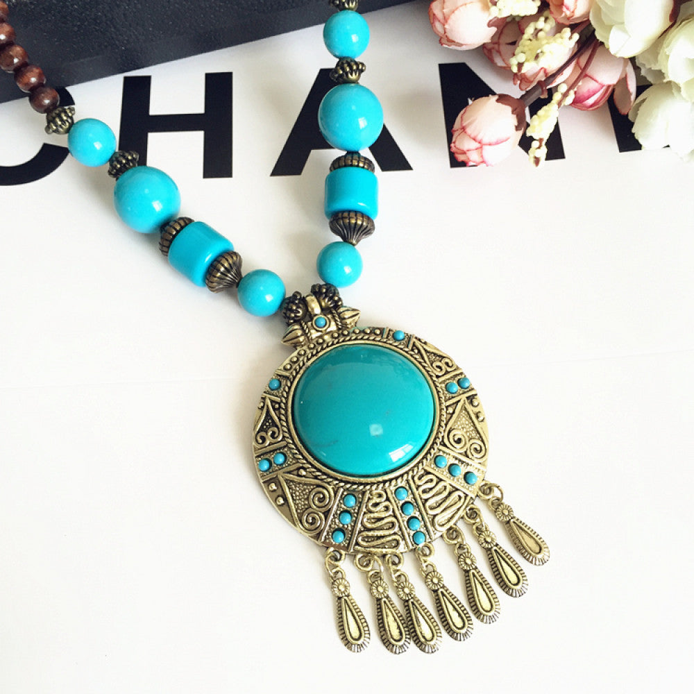 Vintage bohemian ethnic necklace with large red pendant, turquoise details, and tassel design, featuring antique bronze finish, ideal for boho fashion, displayed with floral and text accents against a white background 9