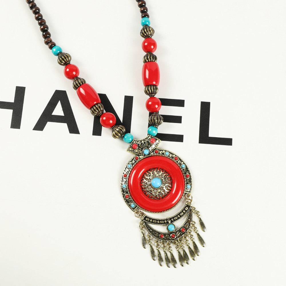 Vintage bohemian ethnic necklace with red pendant, turquoise accents, and tassel design, featuring antique bronze details, displayed against a black background with fashion text and Eiffel Tower accent, ideal for boho fashion enthusiasts 01