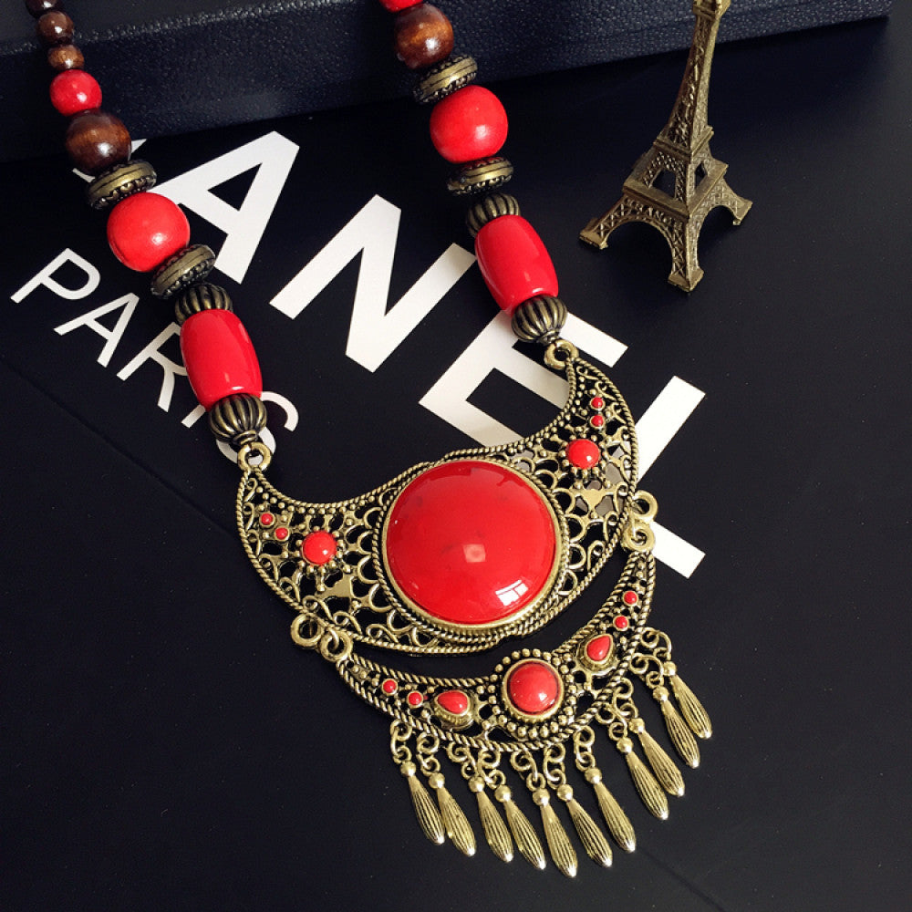 Vintage bohemian ethnic necklace with red pendant, turquoise accents, and tassel design, featuring antique bronze details, displayed against a black background with fashion text and Eiffel Tower accent, ideal for boho fashion enthusiasts 06