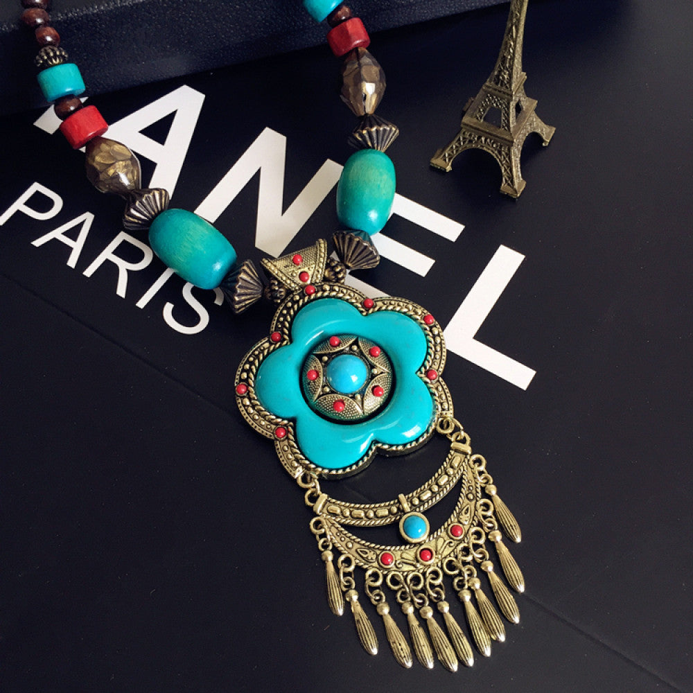 Vintage bohemian ethnic necklace with red pendant, turquoise accents, and tassel design, featuring antique bronze details, displayed against a black background with fashion text and Eiffel Tower accent, ideal for boho fashion enthusiasts 07
