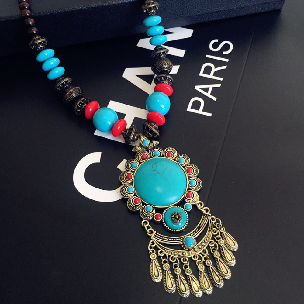 Vintage bohemian ethnic necklace with red pendant, turquoise accents, and tassel design, featuring antique bronze details, displayed against a black background with fashion text and Eiffel Tower accent, ideal for boho fashion enthusiasts  09