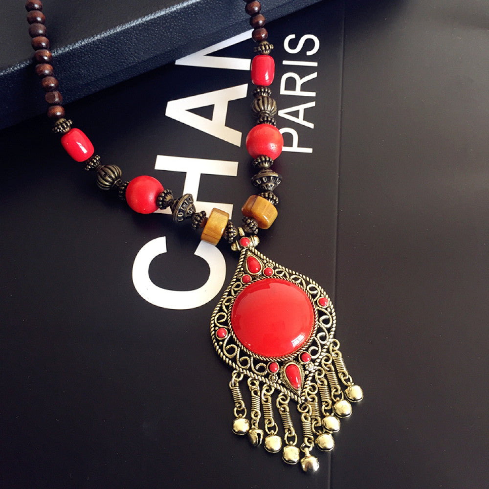 Vintage bohemian ethnic necklace with red pendant, turquoise accents, and tassel design, featuring antique bronze details, displayed against a black background with fashion text and Eiffel Tower accent, ideal for boho fashion enthusiasts 10