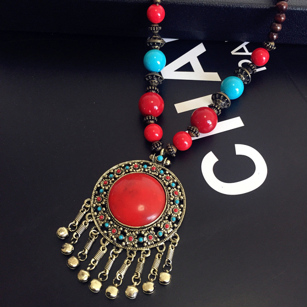 Vintage bohemian ethnic necklace with red pendant, turquoise accents, and tassel design, featuring antique bronze details, displayed against a black background with fashion text and Eiffel Tower accent, ideal for boho fashion enthusiasts 12