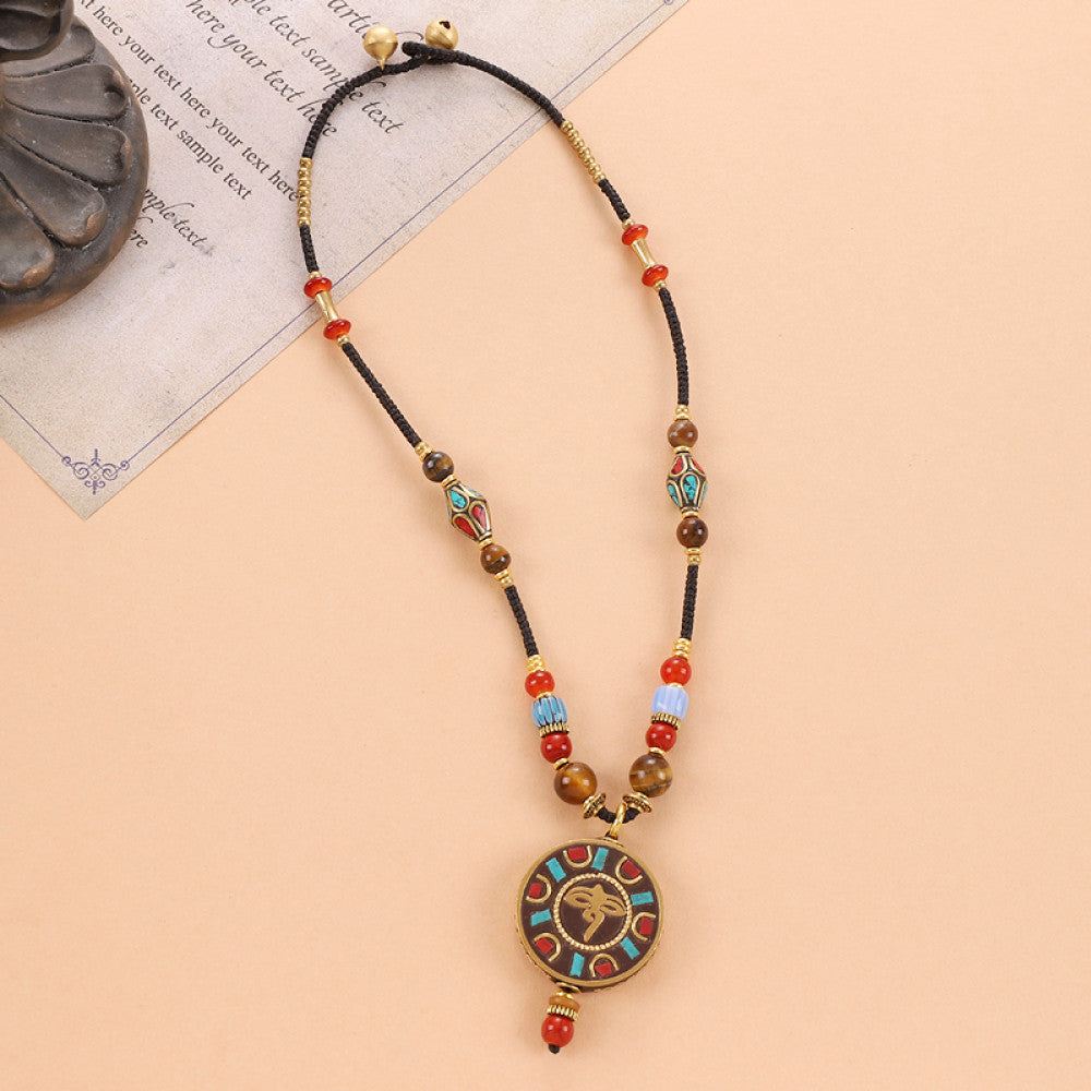 Vintage bohemian ethnic tribal beaded necklace with intricate colorful pendant and multi-color beads, ideal for boho fashion, displayed on a neutral background with vintage paper accent