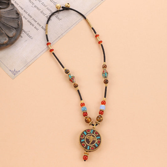 Vintage bohemian ethnic tribal beaded necklace with intricate colorful pendant and multi-color beads, ideal for boho fashion, displayed on a neutral background with vintage paper accent
