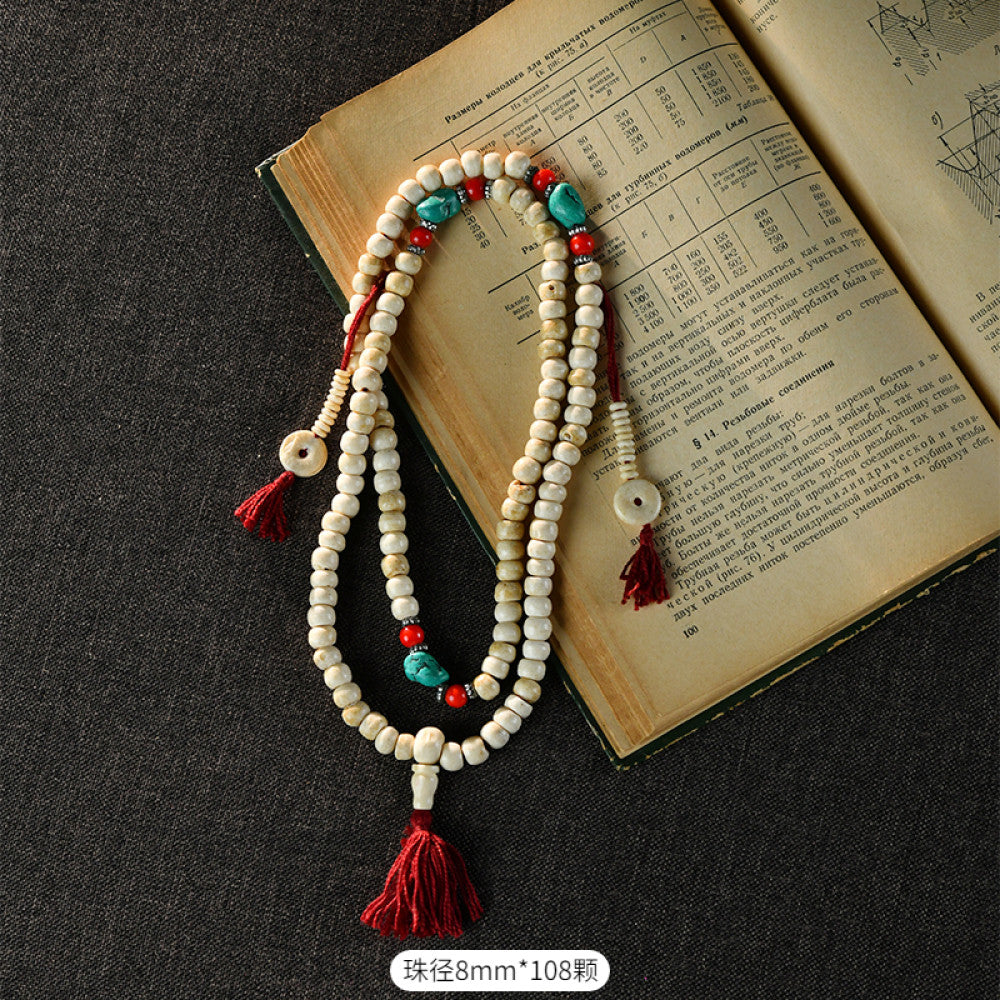 Vintage bohemian ethnic tribal multi-layer beaded necklace with turquoise accents and red tassels, displayed on an old book, ideal for spiritual boho fashion and layering