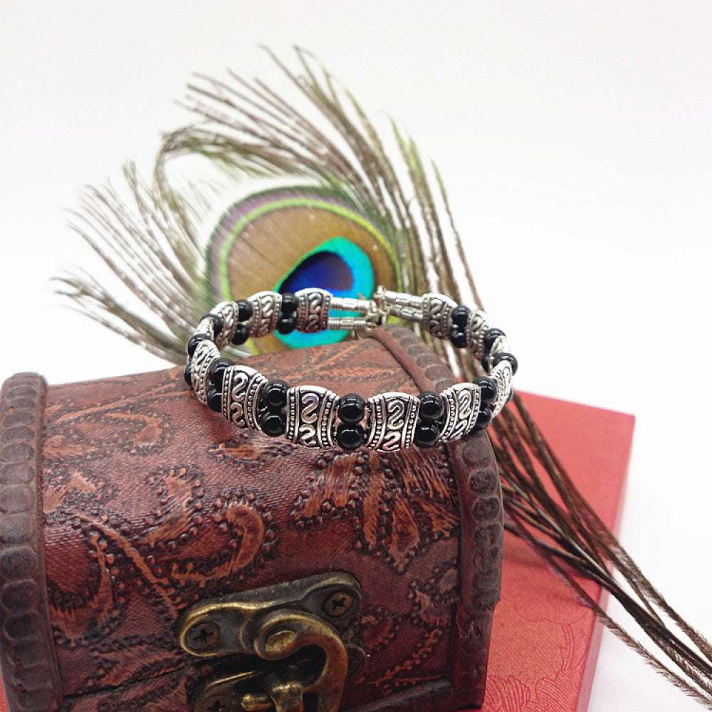 Vintage bohemian ethnic turquoise beaded bracelet with silver engraved accents, displayed on a patterned vintage box with peacock feathers, ideal for boho and ethnic fashion enthusiasts 01