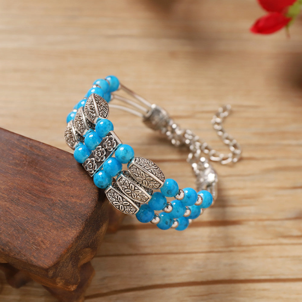 Vintage bohemian ethnic bracelet with turquoise beads and silver leaf accents, displayed on a wooden surface, ideal for boho fashion enthusiasts
