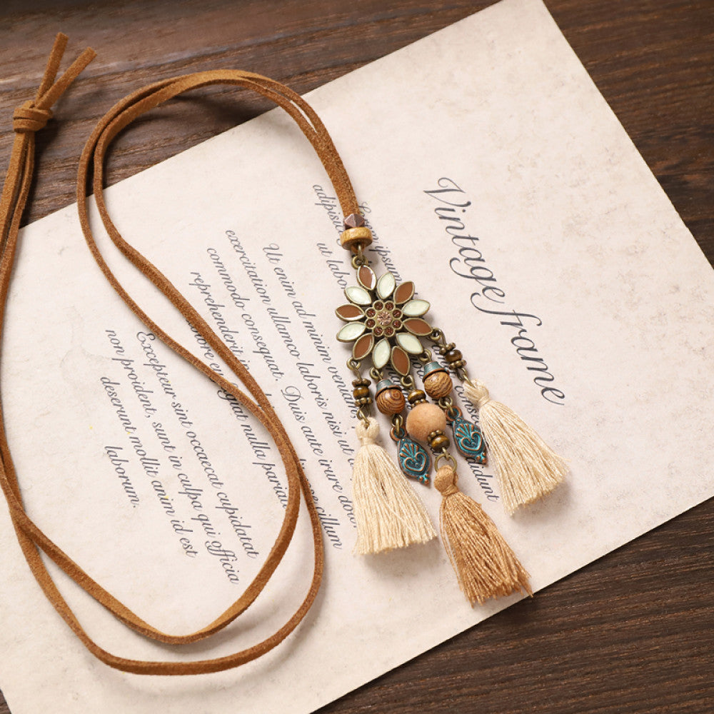Vintage bohemian floral tassel necklace with beaded and fringe details, featuring earthy tones and intricate design, displayed on vintage paper, ideal for boho fashion enthusiasts