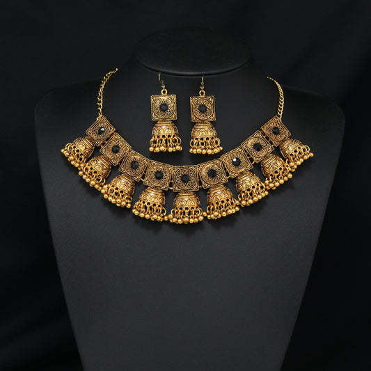Vintage bohemian ethnic gold-tone necklace and earring set with intricate jhumka design, ideal for traditional or boho-chic occasions, displayed on a black mannequin against a dark background