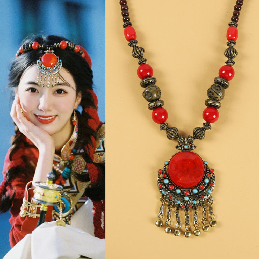 Ethnic tribal style necklace with large red pendant, colorful beaded design, and tassel details, perfect for bohemian vintage fashion, showcased alongside a model in traditional ethnic attire