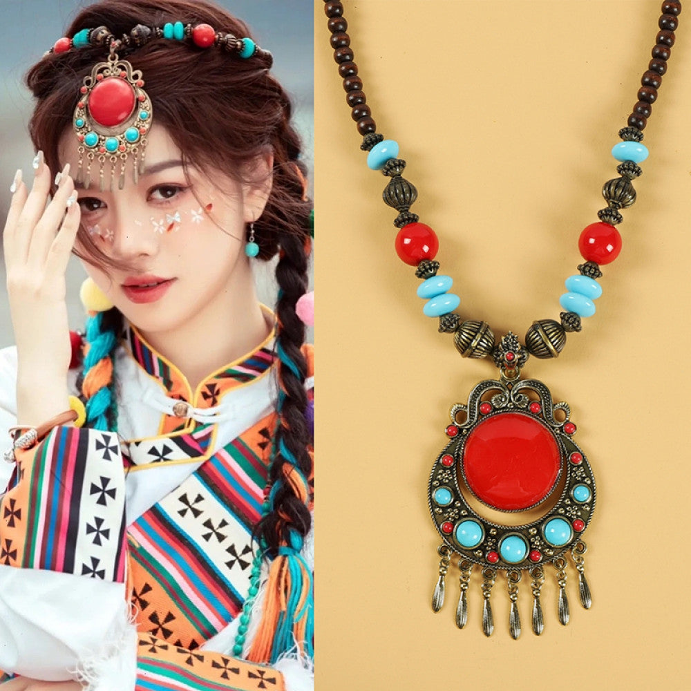 Ethnic tribal style necklace with large red pendant, colorful beaded design, and tassel details, ideal for bohemian vintage fashion, displayed alongside a model in traditional ethnic attire
