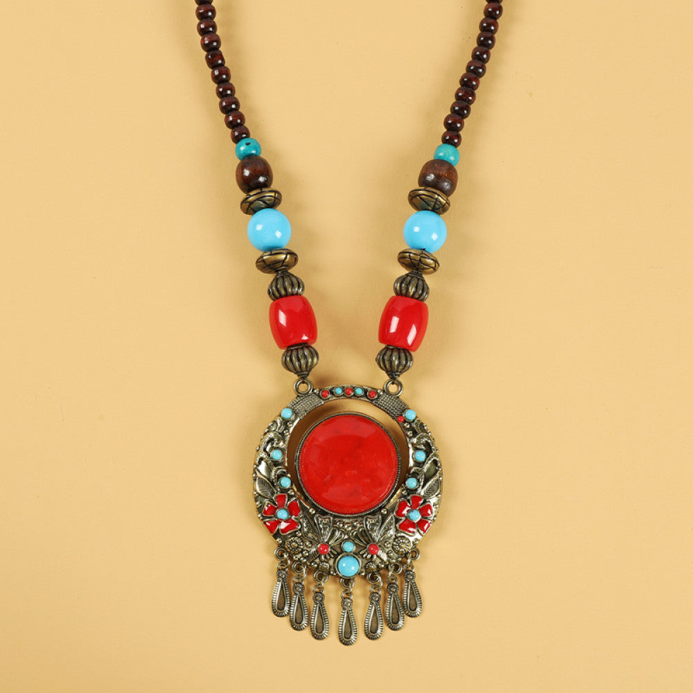 Ethnic tribal style necklace with large red pendant, colorful beaded design, and tassel details, ideal for bohemian vintage fashion, displayed alongside a model in traditional ethnic attire 06