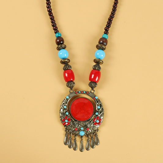 Ethnic tribal style necklace with large red pendant, colorful beaded design, and tassel details, ideal for bohemian vintage fashion, displayed alongside a model in traditional ethnic attire 06