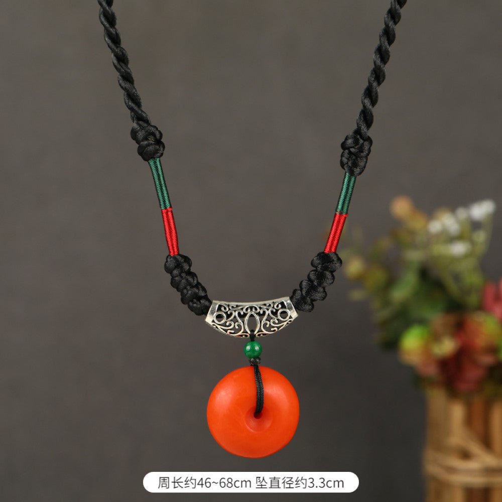 Vintage bohemian ethnic tribal necklace featuring a red circular pendant, intricate silver detailing, and braided rope design, perfect for boho fashion, showcased against a neutral background