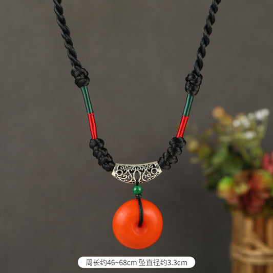 Vintage bohemian ethnic tribal necklace featuring a red circular pendant, intricate silver detailing, and braided rope design, perfect for boho fashion, showcased against a neutral background