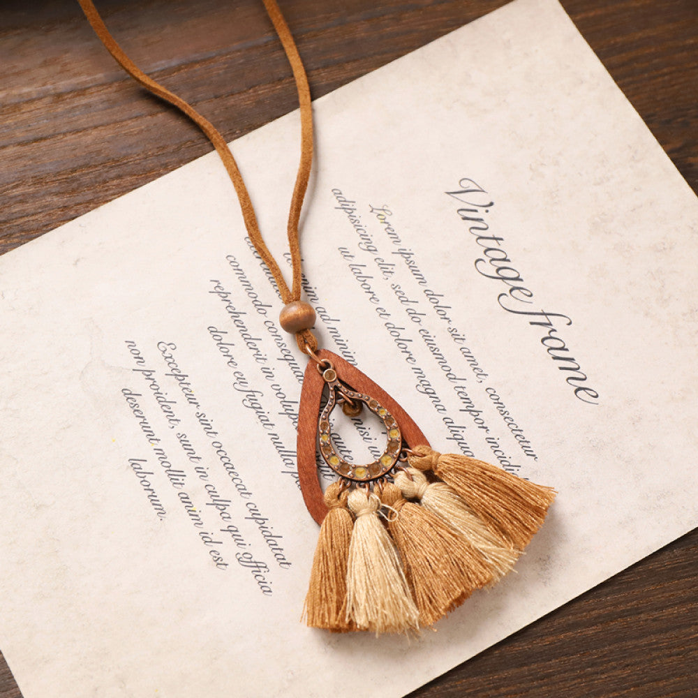 Vintage bohemian tassel necklace with earthy tone fringe and intricate pendant, displayed on vintage paper, ideal for boho fashion enthusiasts