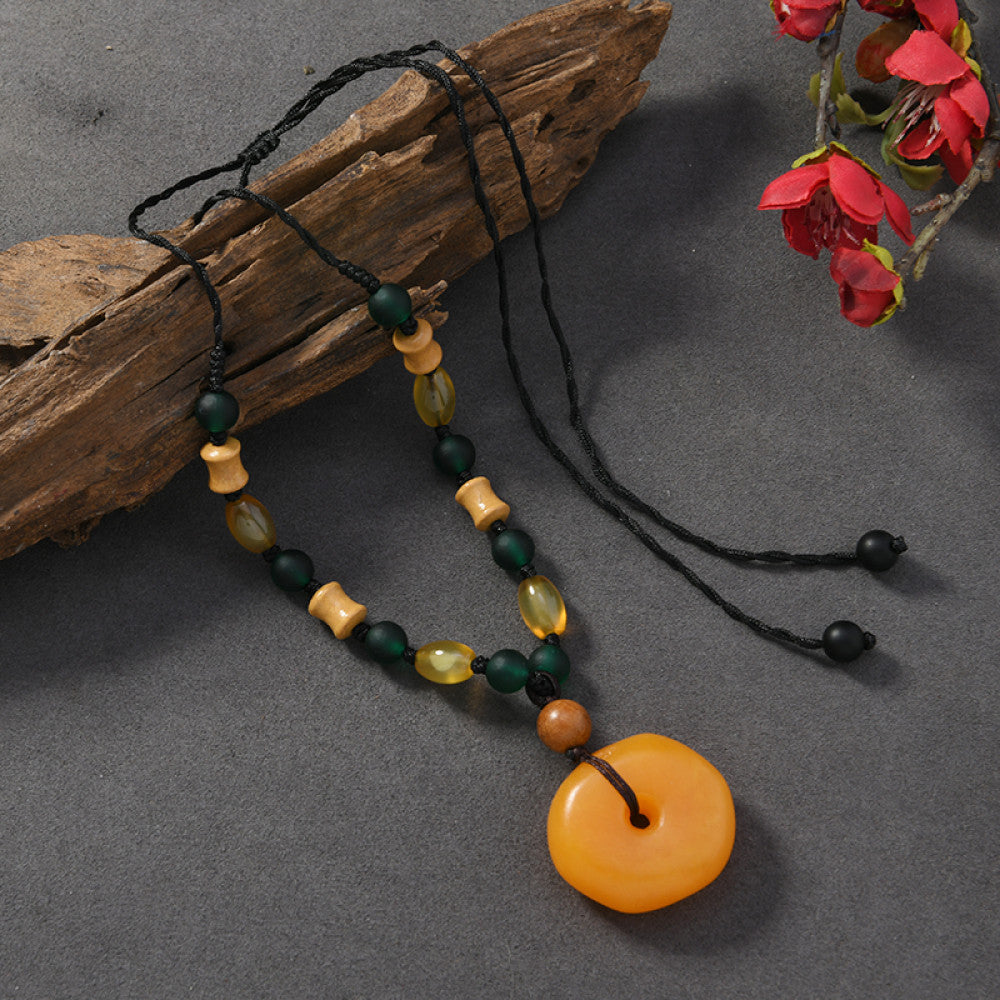 Vintage bohemian ethnic tribal necklace with wooden flower pendants and red beads, featuring a braided rope design, displayed with driftwood and red flowers for a nature-inspired boho look 01