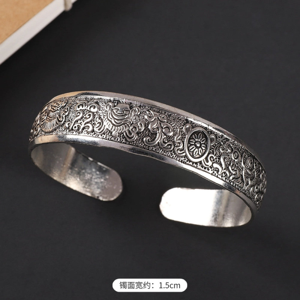 Vintage bohemian ethnic silver-tone engraved filigree cuff bracelet with intricate floral designs, displayed on black surface, ideal for boho and ethnic fashion enthusiasts