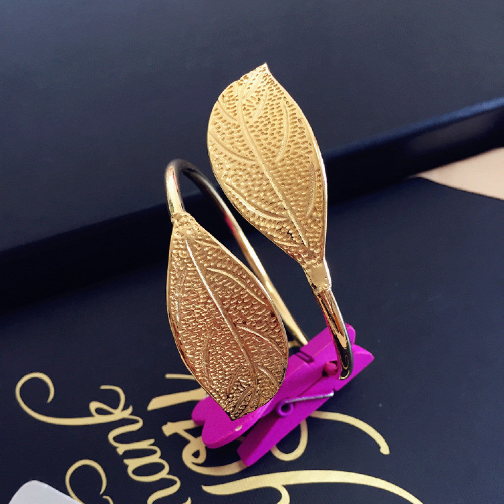 Boho fashion luxury gold leaf cuff bangle with textured leaf design, styled on a decorative surface, ideal for nature-loving and bohemian fashion enthusiasts in the US