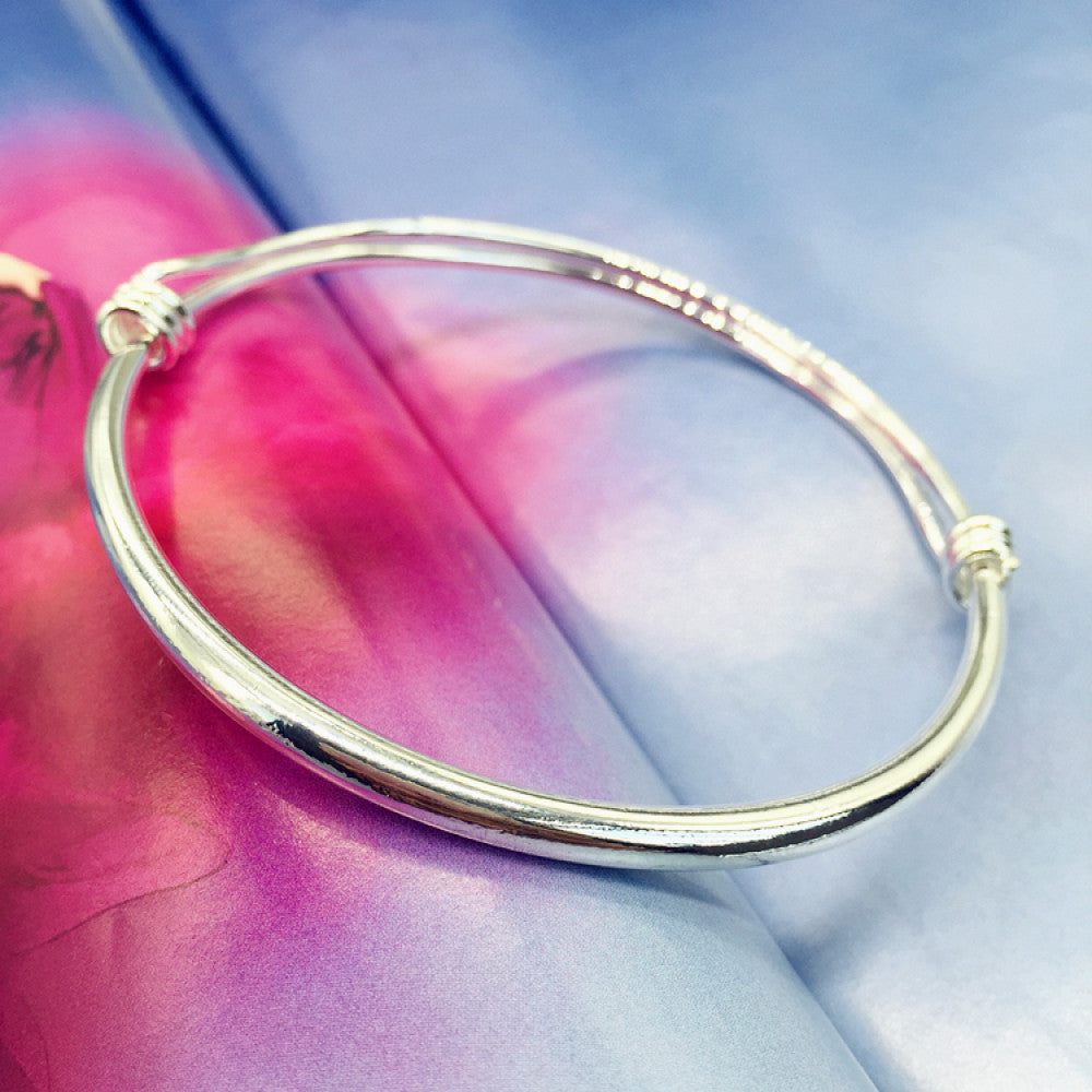Boho minimalist polished silver adjustable bangle, styled on a colorful surface, ideal for minimalist and bohemian fashion enthusiasts