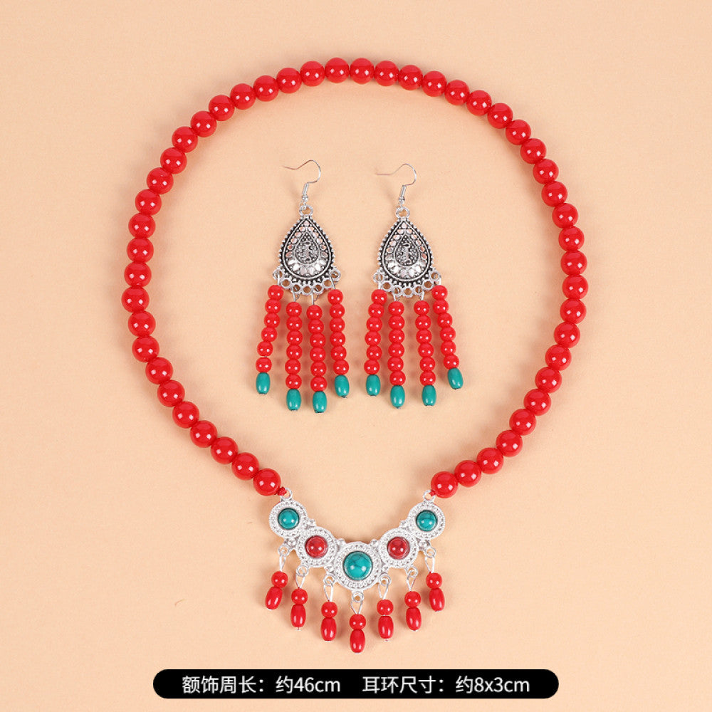 Boho red beaded choker necklace featuring smooth red bead strands, silver-tone decorative centerpiece (with turquoise & red gemstone accents), and red tassel pendants, displayed on a light beige background with red floral decor, ideal for bohemian and traditional fashion enthusiasts in the US 02